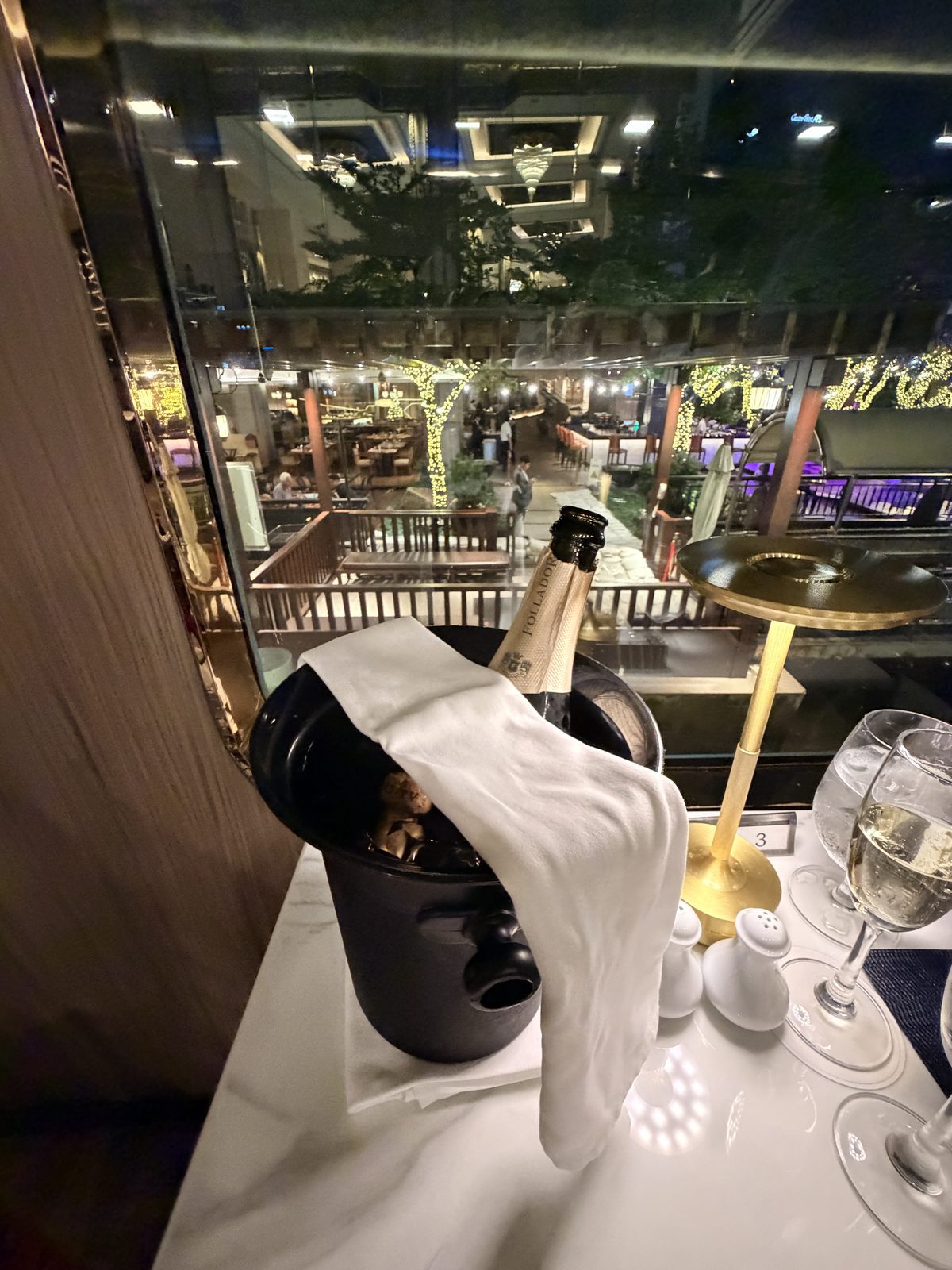 香格里拉地平線號晚餐遊船靠窗餐桌上冰鎮的香檳與精緻餐具