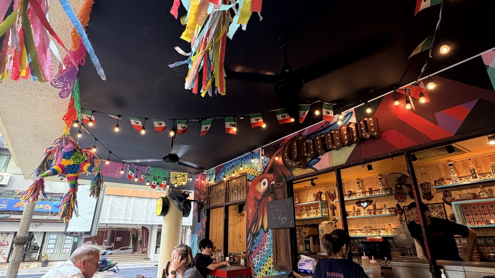La Lupita Bangkok 半戶外餐廳內的彩色剪紙旗幟、開放式吧檯與座位