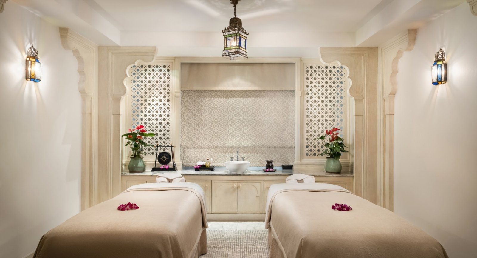 Spa 雙人療程室，兩張按摩床上擺著花瓣，牆面是白色拱形壁龕