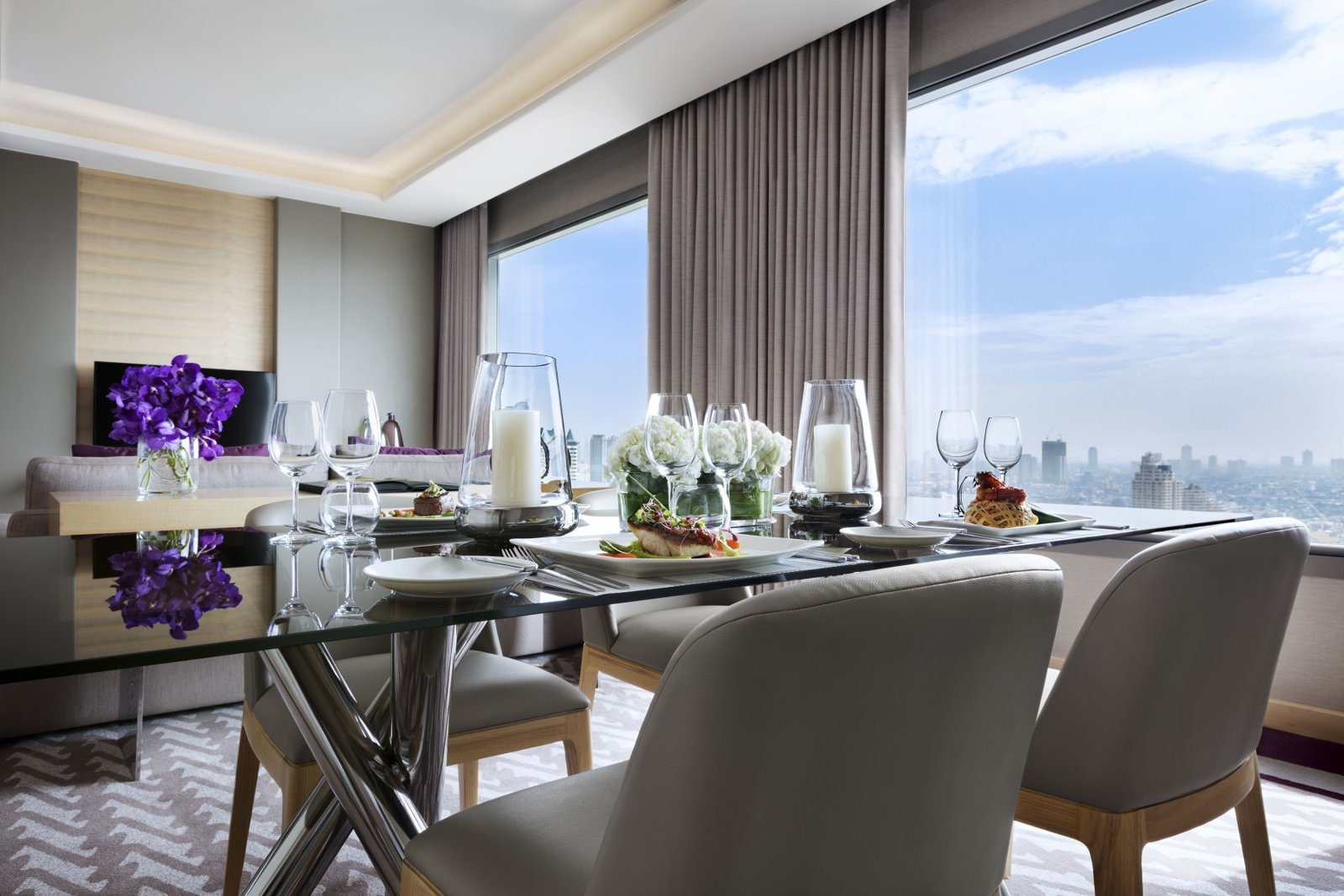 河景套房的玻璃餐桌擺好餐具，窗外是寬闊的河景