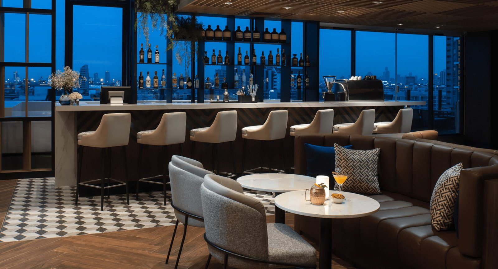 傍晚的 Greenhouse Terrace Bar，吧台與沙發座位外是城市夜色