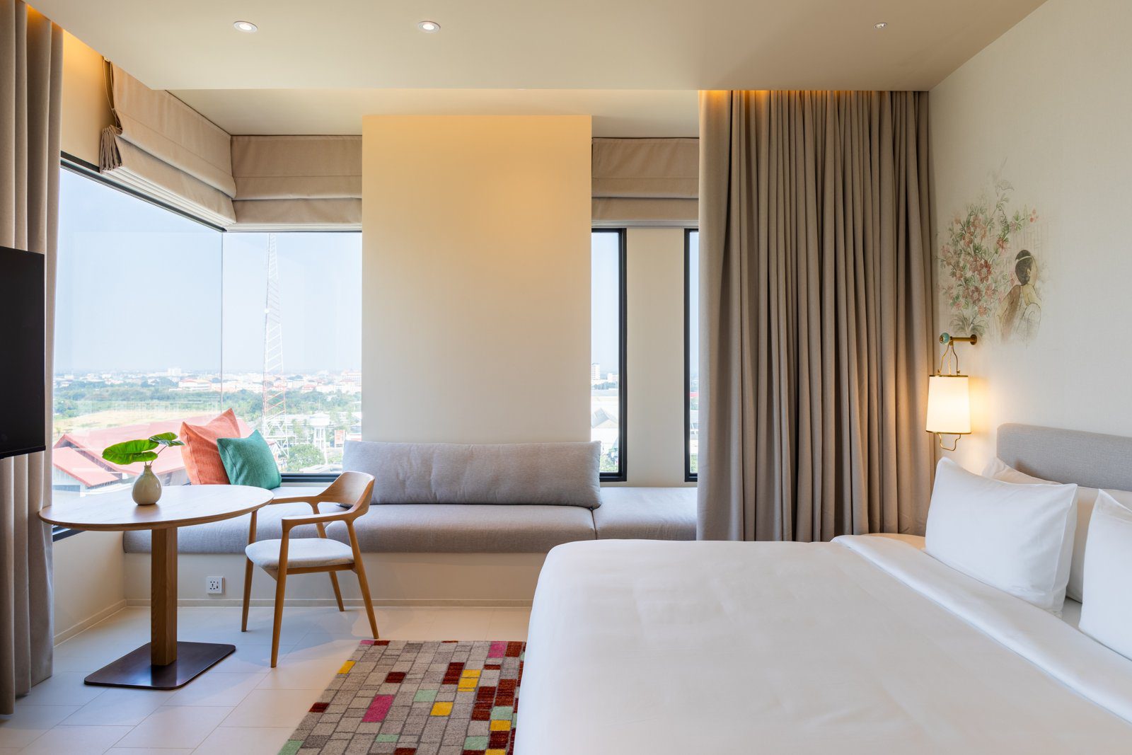 明亮的客房裡一張大床靠窗，轉角落地窗外是大城的樓房與樹林