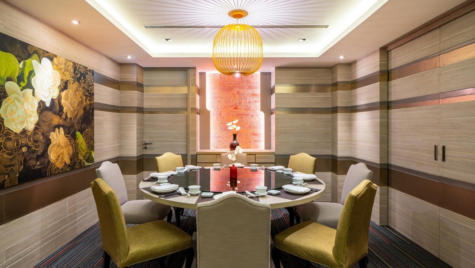 中式包廂裡的圓桌擺好餐具，牆上是深色底的大朵花卉畫，天花板垂著一盞圓形吊燈