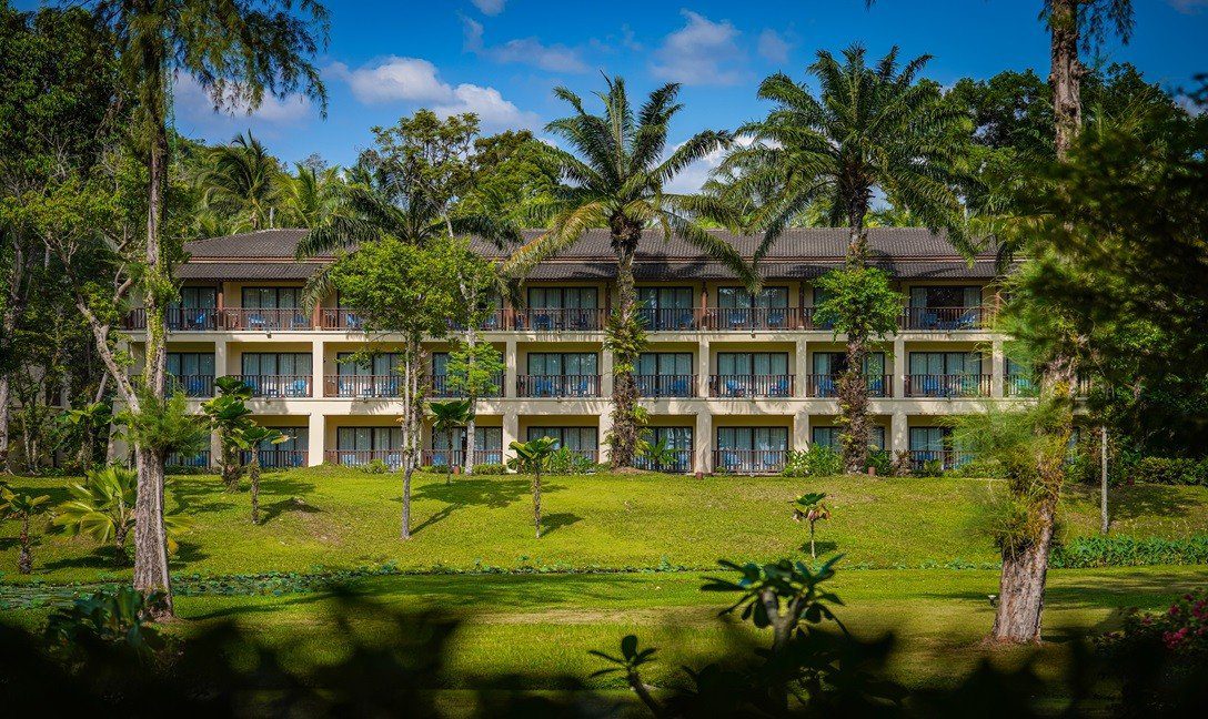 綠色草坪與椰子樹後方的低層客房建築