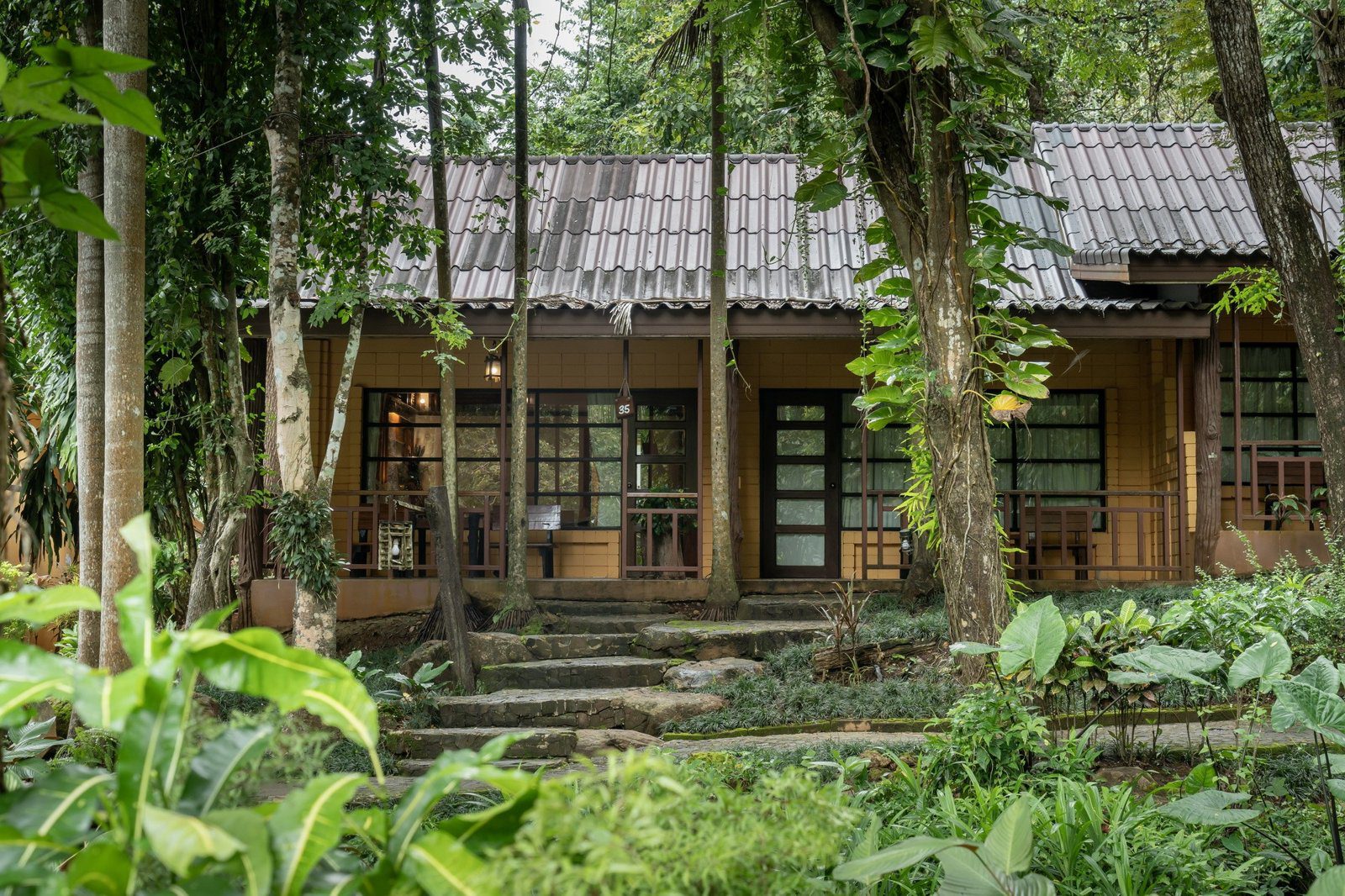 石階與熱帶植物之間是一棟木造長屋，屋前有木造露台