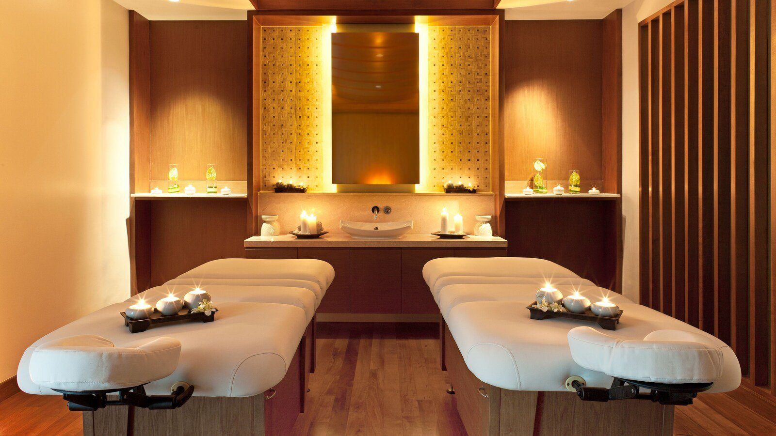 Spa 療程室裡並排的兩張按摩床，牆面是木作格柵與暖色燈光