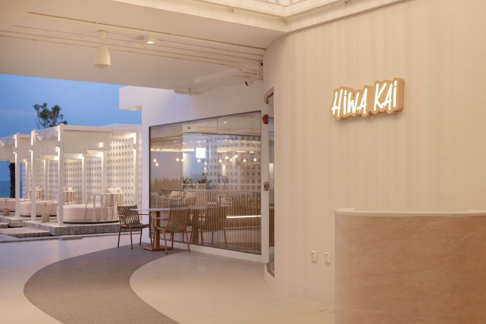 餐廳入口的牆上寫著 HIWA KAI，外面是白色鏤空牆的戶外座位