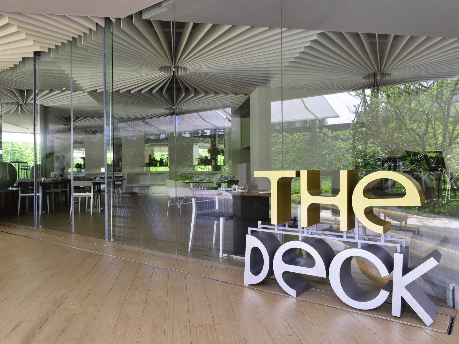 餐廳入口立著 THE DECK 大字招牌，天花板是放射狀的木條造型